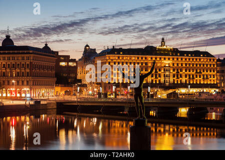 Statue par des bâtiments au coucher du soleil à Stockholm, Suède Banque D'Images