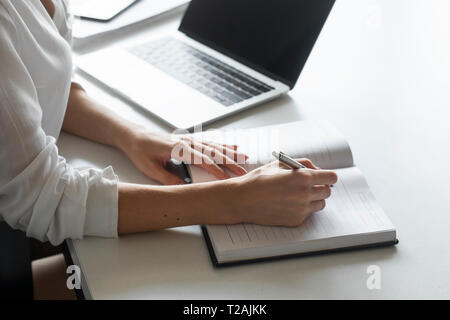 Part of young businesswoman writing notes at desk Banque D'Images
