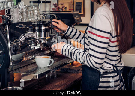 Barista asiatique femme faire le café cappuccino au café avec la machine à café dans le bar comptoir,Nourriture et boissons service concept. Banque D'Images