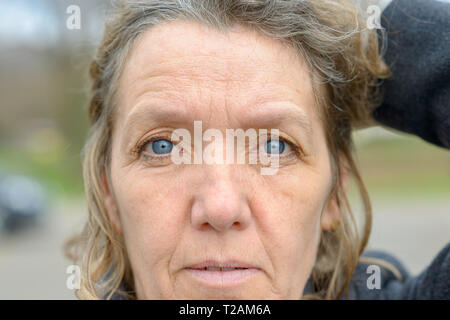 Visage de femme d'âge moyen aux yeux bleus, visage ridé et les cheveux bouclés, looking at camera Banque D'Images