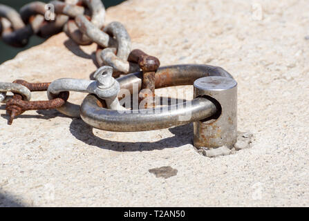 Rusty metal ancienne borne d'amarrage avec une chaîne enroulée autour. Banque D'Images