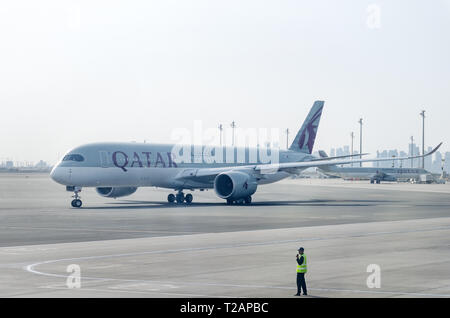 Doha, Qatar, 2018-05-01 : par avion Qatar Airlines quitte le parking. Placier contrôle le mouvement de l'aéronef. L'équipe au sol de l'aéroport. Banque D'Images