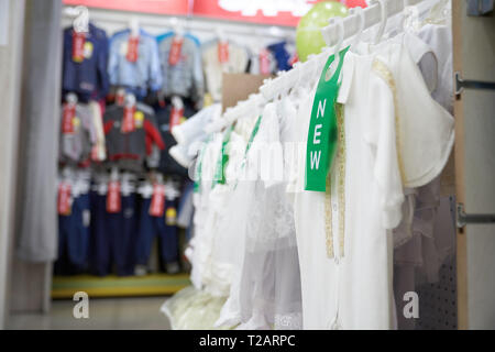 Grand choix de vêtements élégants et modernes dans le quartier branché de grand magasin. Blouse blanche sur t shirts sur des cintres. De nouveaux vêtements pour filles et garçons en shoppi Banque D'Images
