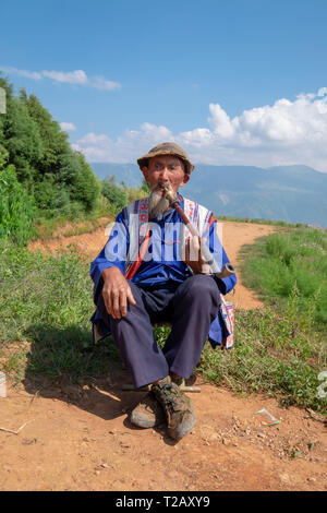 Homme mature local fumant une pipe à un petit village dans les montagnes près de Kumming, province du Yunnan dans le sud-ouest de la Chine en septembre Banque D'Images