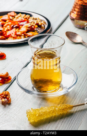 Tisane dans verre oriental arabe avec délices de l'écrou sur la plaque de métal sur la surface en bois clair Banque D'Images