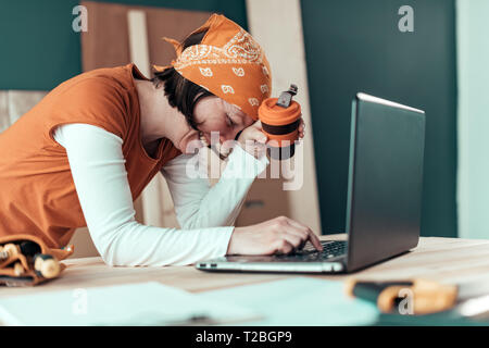 Happy smiling female carpenter lors de chat en ligne avec le client sur un ordinateur portable dans l'atelier de menuiserie Banque D'Images