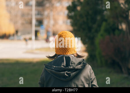 Vue arrière du casual female personne marchant sur la rue sous le soleil de matin de printemps