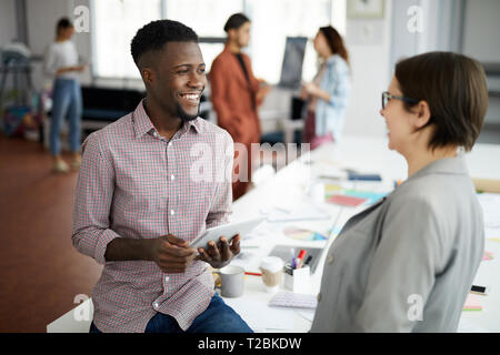 Beau Portrait de l'homme afro-américain de parler à tes collègues et souriant tout en travaillant dans un bureau moderne, copy space Banque D'Images