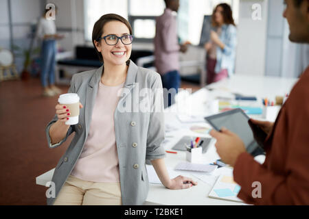 Portrait of young businesswoman smiling heureusement réussi tout en parlant à collègue pendant pause café dans office, copy space Banque D'Images