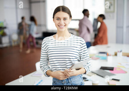 Taille de young woman smiling at camera while posing in office, copy space Banque D'Images