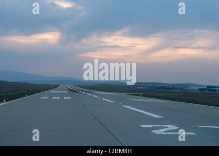 La piste de l'aéroport semble aller vers l'horizon au coucher du soleil Banque D'Images