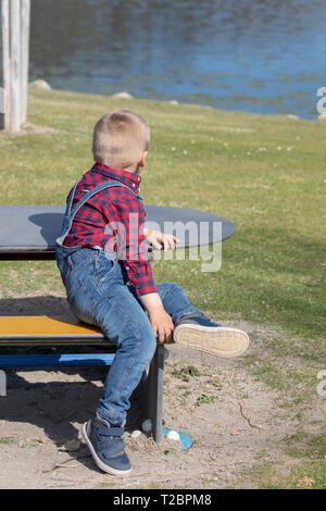 Les enfants sont assis sur un banc en bois à l'air libre Banque D'Images