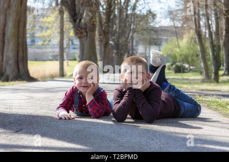 Portrait of happy brothers étendue sur le sol dans la région de park et looking at camera Banque D'Images