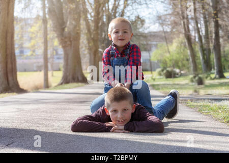 Portrait of happy brothers étendue sur le sol dans la région de park et looking at camera Banque D'Images