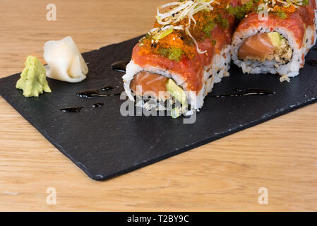 Rouleau spécial de riz avec saumon, avocat, différents types de caviar servi sur une dalle d'ardoise avec wasabi et gari Banque D'Images