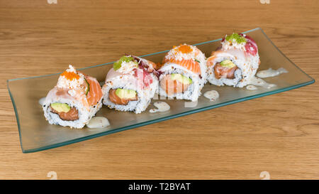 Uramaki spécial, le riz farci au saumon avocat, couverts de sashimi de thon rouge et la mer basse, assaisonné de sauce au fromage, des galles sur un plat Banque D'Images