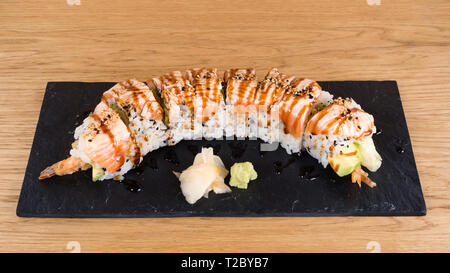 Uramaki spécial, le riz farci aux crevettes tempura, salade verte, avocat, couvert de saumon grillé, assaisonné de sésame noir et blanc, Tamar Banque D'Images