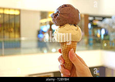 Deux boules de beurre d'arachide et chocolat ice cream cone dans woman's hand Banque D'Images