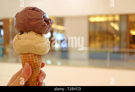 Woman's hand holding ice cream cone avec deux boules de glace au chocolat et beurre d'arachide Banque D'Images