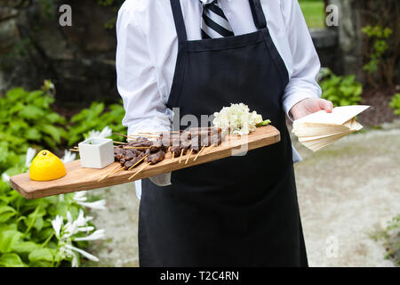 Un serveur qui contient un plateau en bois plein de collations de viande au cours d'un événement Banque D'Images