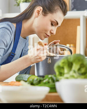 Belle fille, c'est nourriture d'échantillon et souriant pendant la cuisson dans la cuisine à la maison. Banque D'Images