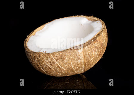 Une moitié de noix de coco bio frais isolé sur verre noir Banque D'Images