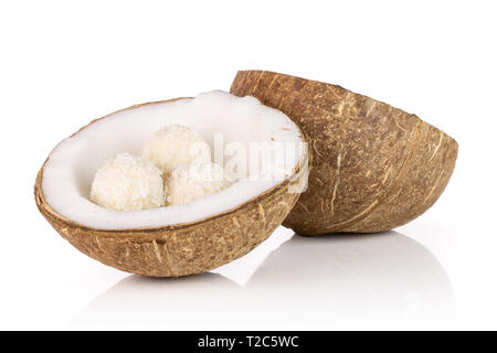 Groupe de deux moitiés de noix de coco fraîche bio avec trois petites boules de cacao isolé sur fond blanc Banque D'Images
