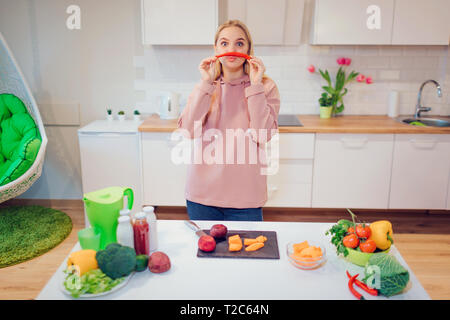 Vegan belle blonde femme a l'amusement avec chilli peper pendant la cuisson des légumes crus dans la cuisine. Régime cru de nourriture. La nourriture végétarienne. La saine alimentation Banque D'Images