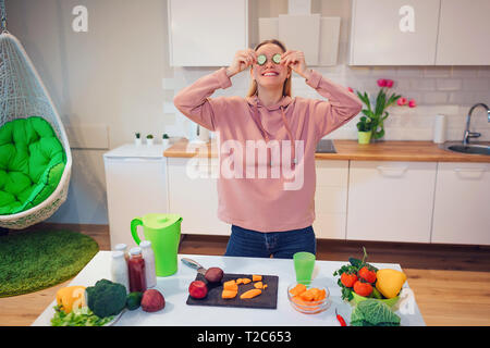 Vegan belle blonde femme a du plaisir avec le concombre pendant la cuisson des légumes crus dans la cuisine. Régime cru de nourriture. La nourriture végétarienne. La saine alimentation Banque D'Images