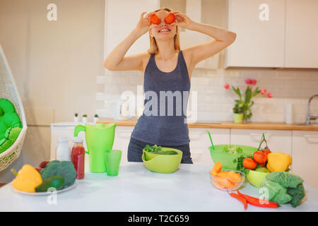 Vegan belle blonde femme a l'amusement avec les tomates biologiques pendant la cuisson des légumes crus dans la cuisine. Régime cru de nourriture. La nourriture végétarienne. La saine alimentation Banque D'Images