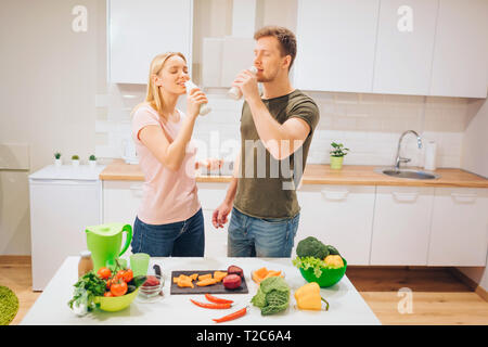 Les jeunes vegan famille aimante boissons smoothie naturel pendant la cuisson des légumes crus dans la cuisine. Le régime alimentaire de désintoxication. Heureux couple. Régime cru de nourriture. Des plats végétariens Banque D'Images