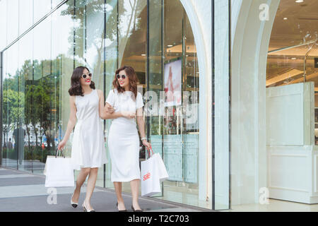 La vente, la consommation et les gens heureux concept - les jeunes femmes avec shopping bags on city street Banque D'Images