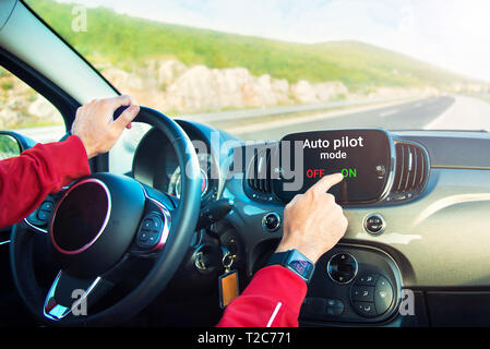 Les mains des hommes avec smart watch sur la commutation sur le pilote automatique sur le mode d'affichage de voiture sur l'autoroute Banque D'Images