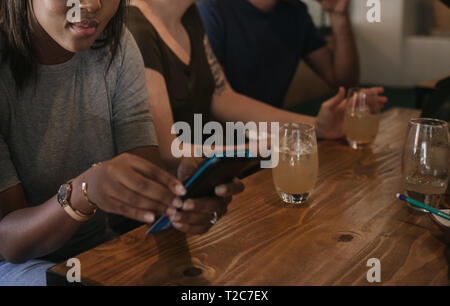 Client de payer pour un projet de loi avec une machine de carte de crédit tout en profitant d'une soirée entre amis dans un bar Banque D'Images