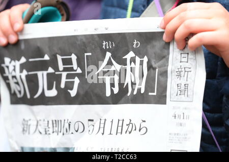 Un garçon est titulaire d'une copie de ces rapports édition d'un journal le nom de la nouvelle ère impériale, 'Reiwa', à Tokyo, au Japon, le 1 avril 2019. Le gouvernement japonais a officiellement annoncé la prochaine ère sera connu sous le nom de "ère" Reiwa le lundi, un mois avant Prince héritier Naruhito monte sur le trône après l'abdication de l'Empereur Akihito. Credit : Naoki Nishimura/AFLO/Alamy Live News Banque D'Images