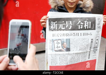 Un garçon est titulaire d'une copie de ces rapports édition d'un journal le nom de la nouvelle ère impériale, 'Reiwa', à Tokyo, au Japon, le 1 avril 2019. Le gouvernement japonais a officiellement annoncé la prochaine ère sera connu sous le nom de "ère" Reiwa le lundi, un mois avant Prince héritier Naruhito monte sur le trône après l'abdication de l'Empereur Akihito. Credit : Naoki Nishimura/AFLO/Alamy Live News Banque D'Images