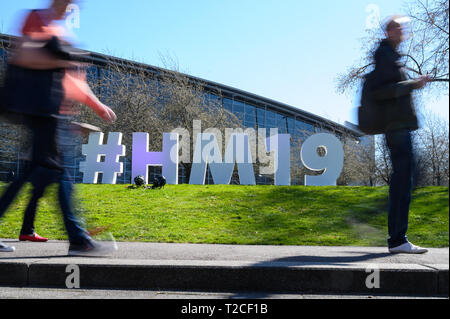 Hanovre, Allemagne. 01 avr, 2019. Visiteurs passent par un '# HM19' affichage à la foire de Hanovre. Credit : Christophe Gateau/dpa/Alamy Live News Banque D'Images