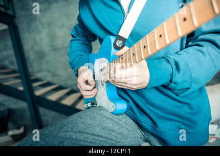 Musicien professionnel dans des sweat-shirt bleu transport guitare électronique Banque D'Images