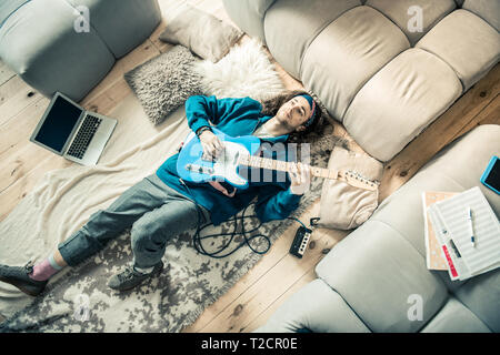 D'émotion brun portant sur marbre couvert avec guitare sur sa poitrine Banque D'Images