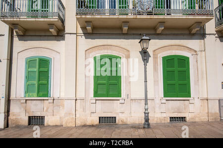 Vue frontale d'un vert en bois fenêtres sur mur jaune. Beau balcon. L'extérieur d'un logement dans la région de Bari, Pouilles, Italie. Région des Pouilles Banque D'Images