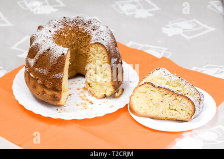 L'anneau fait maison cake saupoudrés de sucre glace on white plate Banque D'Images