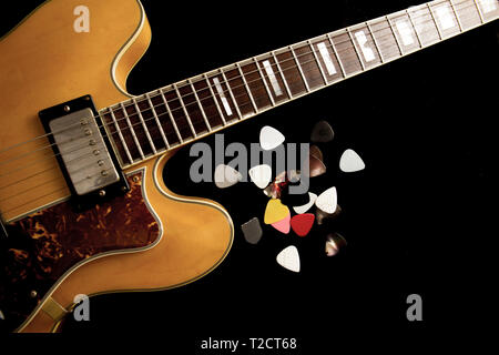 Vintage guitare archtop en érable naturel close-up d'en haut sur fond noir avec divers picks Banque D'Images