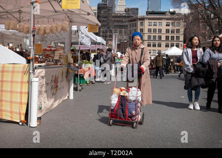 Une femme plus âgée poussant un caddie rempli d'achats. Dans la région de Union Square Park à Manhattan, New York City. Banque D'Images
