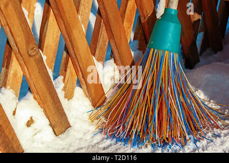 Un balai en plastique avec des soies multicolores de la pile se trouve dans la neige. Le concept de nettoyage de la zone de neige en hiver.Close-up de l'obj Banque D'Images