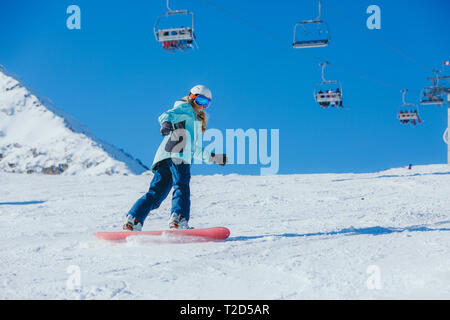 Snowboarder dans les montagnes. Jeune fille sur une planche à neige descend de la montagne. Banque D'Images