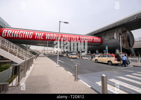 Les passagers qui quittent un taxi pour prendre un avion à l'Aéroport International de Dubaï, Émirats Arabes Unis Banque D'Images