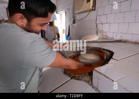 Le pain plat de cuisson Baker l'arabe moyen sur les murs de la pita four tandoor Banque D'Images