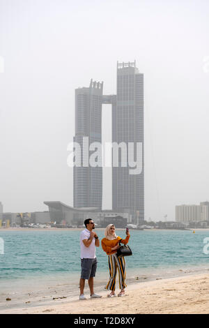 Jeune femme musulmane portant un hijab en tenant un avec un homme selfies sur une plage à Abu Dhabi, Émirats Arabes Unis Banque D'Images