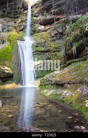 Scenic, cascade soleil ruisselait sur la falaise couverte par mousse verte et c'est reflet dans l'eau Banque D'Images