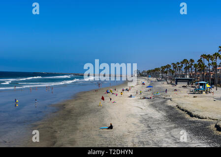 Donnant sur les plages de sable, de palmiers et de l'océan bleu avec des vagues roulant sur rivage sous ciel bleu. Banque D'Images